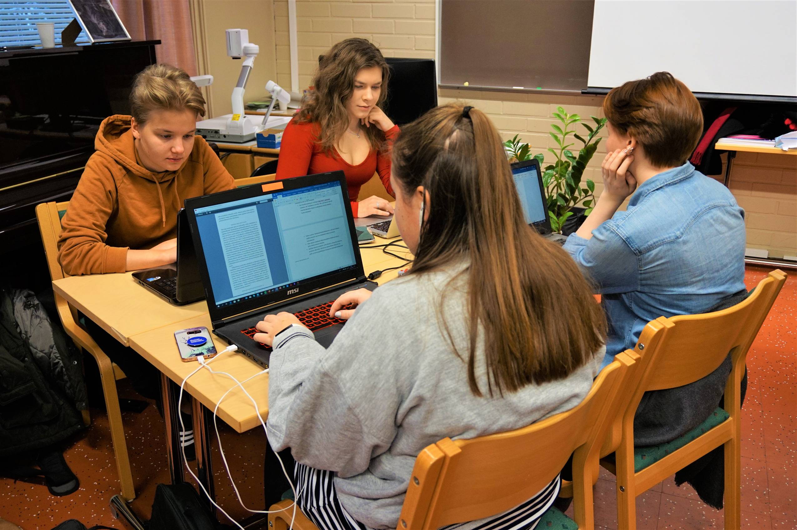 Neljä opiskelijaa työskentelee tietokoneilla pöydän ääressä